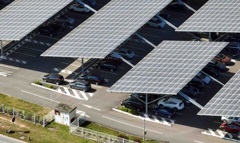 Solar panels installed in parking lot with parked cars