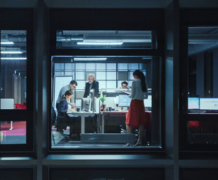 Shot from outside the window. Businessmen and businesswomen working in the office analyzing matters .