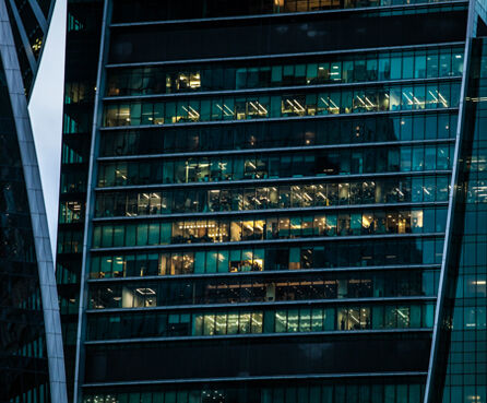 Close up of skyscraper building with office windows, evening view with turned lights